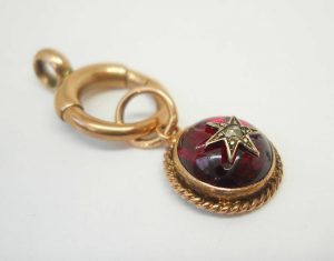 Victorian star set garnet 9ct gold charm on a 9ct gold bolt ring, both circa 1900