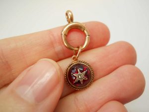 Victorian star set garnet 9ct gold charm on a 9ct gold bolt ring, both circa 1900